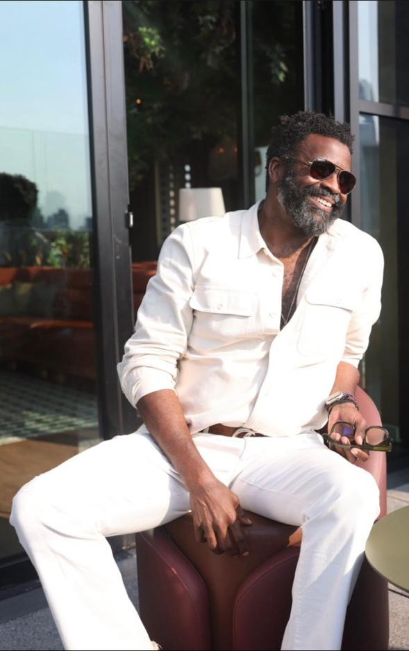 Erik Moore -- seated, all-white outfit on a rooftop terrace